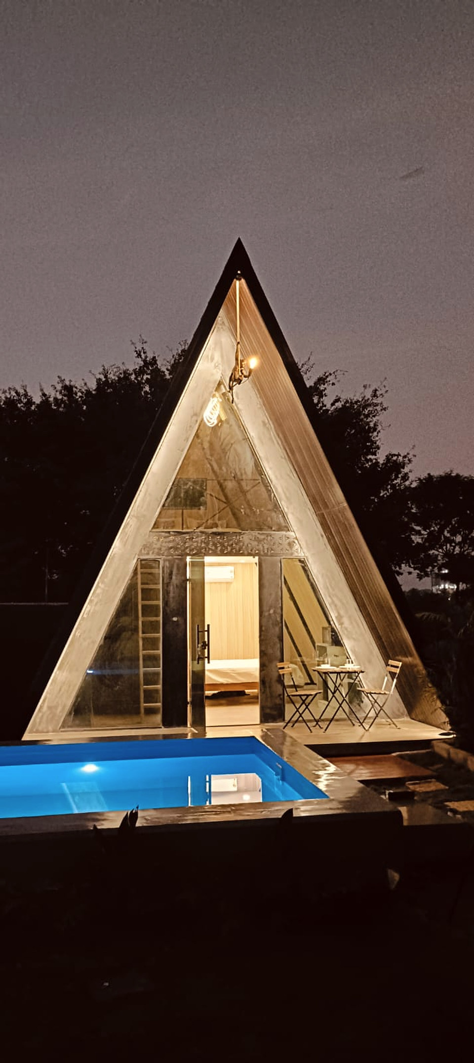 Tall illuminated A-frame cottage at night