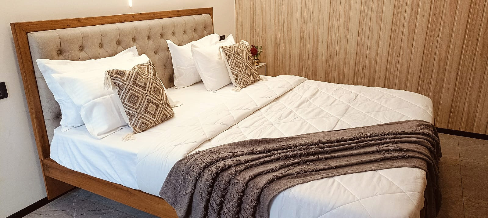 Spacious bedroom with crisp white bedding and warm timber walls